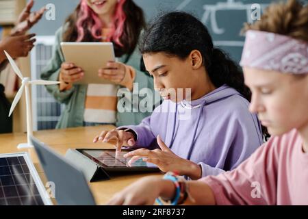 Studentessa che usa gadget durante la lezione insieme ai suoi compagni di classe Foto Stock