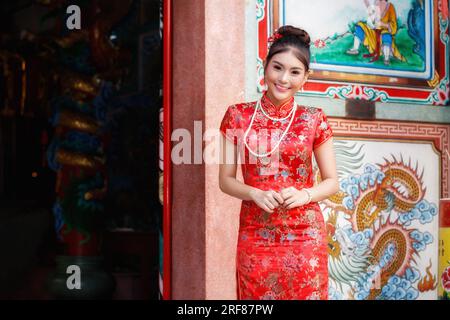 La donna cinese con un abito rosso cheongsam rende omaggio al dio cinese al santuario. Concetto per festeggiare il Capodanno cinese. Foto Stock