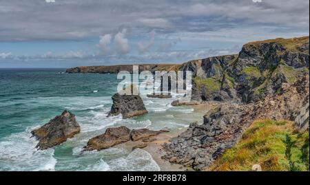 Un paesaggio panoramico che mostra l'alta marea che copre una spiaggia sabbiosa di Bedruthan dopo aver attraversato gli enormi "scalini" di questa splendida e suggestiva posizione. Foto Stock