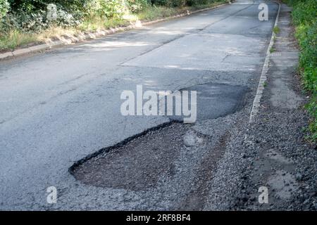 Stoke Poges, Regno Unito. 1 agosto 2023. Parte della superficie stradale sulla B416, Stoke Road a Stoke Poges, nel Buckinghamshire, ha fallito di nuovo. Anche alcuni scarichi sulla strada sono pieni di fango. Un gran numero di veicoli pesanti utilizza la strada per i lavori di costruzione del nuovo South Bucks Country Park, che si sta sviluppando vicino alla A416 appena fuori Slough, sul sito della vecchia Lanes Golf Academy. Il parco di campagna di 59 ettari sarà aperto al pubblico nel 2024. Si ritiene che una parte del materiale rovinato scaricato nel sito sia stata rovinata dai controversi tunnel della ferrovia ad alta velocità HS2, che sono in fase di realizzazione Foto Stock