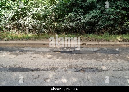 Stoke Poges, Regno Unito. 1 agosto 2023. Parte della superficie stradale sulla B416, Stoke Road a Stoke Poges, nel Buckinghamshire, ha fallito di nuovo. Anche alcuni scarichi sulla strada sono pieni di fango. Un gran numero di veicoli pesanti utilizza la strada per i lavori di costruzione del nuovo South Bucks Country Park, che si sta sviluppando vicino alla A416 appena fuori Slough, sul sito della vecchia Lanes Golf Academy. Il parco di campagna di 59 ettari sarà aperto al pubblico nel 2024. Si ritiene che una parte del materiale rovinato scaricato nel sito sia stata rovinata dai controversi tunnel della ferrovia ad alta velocità HS2, che sono in fase di realizzazione Foto Stock