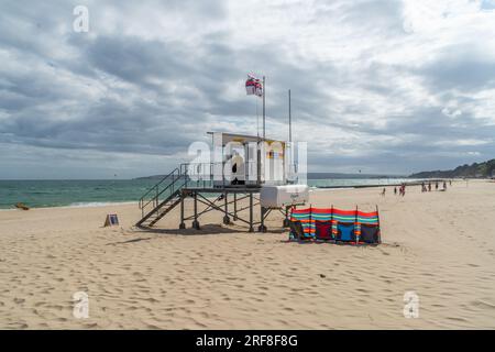 Alum Chine, Bournemouth, Regno Unito - 12 luglio 2023: Bandiera RNLI che sorvola il posto di guardia bagnino sulla spiaggia di fronte al mare. Foto Stock