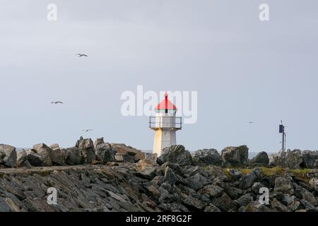 Piccolo faro bianco e rosso alla fine di un muro di banchina contro il cielo blu. Andenes, Andøya, arcipelago di Vesterålen, Nordland, Norvegia settentrionale, Foto Stock