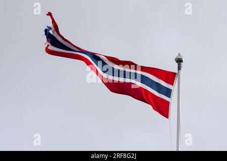 Un pennant norvegese, bandiera, fluttua nel vento fissato su un'asta di bandiera contro un cielo luminoso. Andenes, Andøya, arcipelago di Vesterålen, Nordland, Norvegia Foto Stock