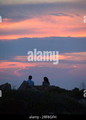 Un ragazzo e una ragazza guardano l'alba da Cabo de Caballería a Minorca. .Un chico y una chica observan la fuesta de Sol desde el cabo de Caballería. Foto Stock