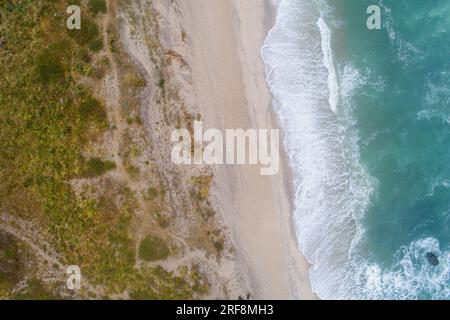 Spettacolare vista dall'alto dalla foto con droni di una splendida spiaggia con rilassante luce solare, onde di mare che martellano la sabbia sulla riva. Calma e rinfresco Foto Stock