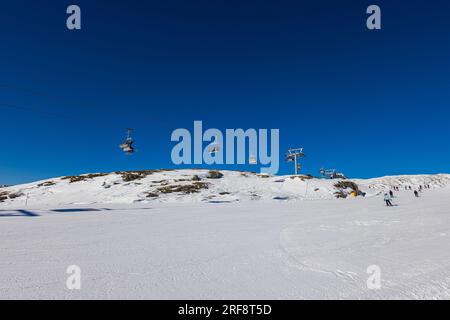 Vista mozzafiato su una montagna innevata nelle Dolomiti, con seggiovia. In lontananza si stagliano maestose vette ricoperte di neve. ascende a. Foto Stock
