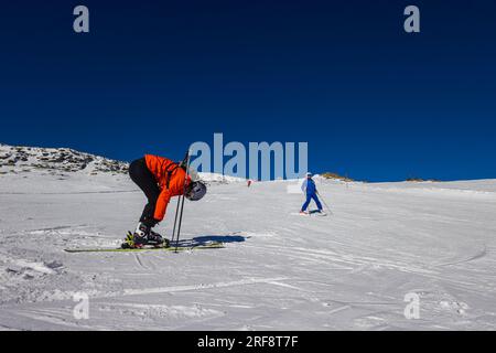 Falcade, Italia - 15 febbraio 2023: Su una pista da sci tra le montagne delle Dolomiti. Lo sciatore stringe la sua legatura prima di iniziare la discesa. Perfetto Foto Stock