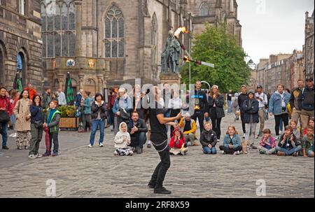 Royal Mile, High Street, Edimburgo, Scozia, Regno Unito. 1 agosto 2023. Chiunque camminasse per High Street avrebbe potuto credere che il Festival Fringe ufficiale di Edimburgo fosse già iniziato quando un grande pubblico cosmopolita si riunì per guardare gli artisti di strada professionisti all'ora del tè. Nella foto: Kozo Kaos intrattiene il pubblico con il suo spettacolo di giocoliere con il fuoco. Credito: AWhite/alamy live news. Foto Stock