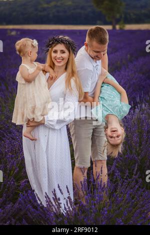 Bella famiglia giovane, padre e madre con due figlie in un pic-nic al campo di lavanda Foto Stock