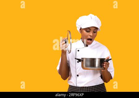 Errore di cottura. Scioccata la donna Black Chef che guarda nella pentola Foto Stock