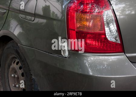 Parafango posteriore e faro di una vettura danneggiati. incidente d'auto. Ammaccatura in metallo, vernice staccata. Caso assicurativo. Riparazione auto. Foto Stock