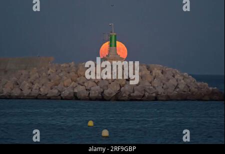 Malaga, Spagna. 1 agosto 2023. La superluna dello storione sorge dietro un faro sulla spiaggia di San Andres. All'inizio di agosto, l'intera superluna dello storione si svolge come uno degli eventi astronomici più sorprendenti del mese. Quando la luna piena ha luogo, appare più grande e più luminosa del normale. Una nuova superluna avrà luogo alla fine di agosto. Credito: SOPA Images Limited/Alamy Live News Foto Stock