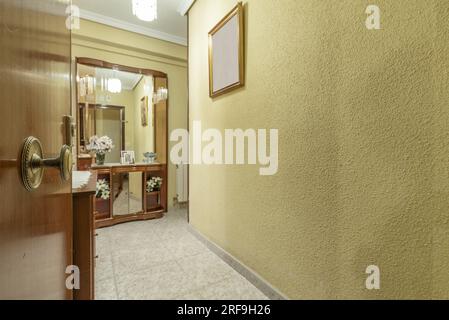 Sala d'ingresso di una casa residenziale con pareti dipinte di giallo con gotelet e una credenza con specchi sullo sfondo Foto Stock