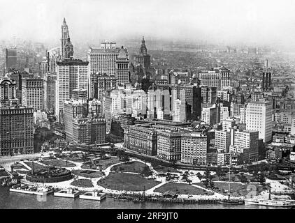 New York, New York: c. 1917 Vista da un aereo della Battery a New York City con l'acquario a sinistra e gli edifici Singer, Woolworth e Equitables sullo skyline dietro di esso. Foto Stock