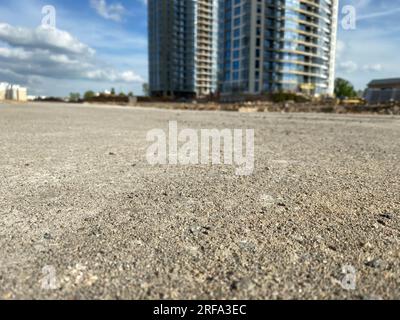 La strada di fronte ad un alto, grande e moderno edificio di un grattacielo in vetro e cemento su un cantiere di una grande città. Foto Stock