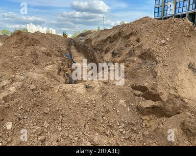 I nuovi tubi dell'acqua in plastica di polietilene di grande diametro, moderni e di grandi dimensioni, si trovano in una fossa sotterranea in un cantiere durante la riparazione di un tubo dell'acqua Foto Stock