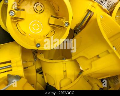 scatole per prese in plastica per riparazione. installazione di impianti elettrici nell'appartamento. chiave a bussola rotonda gialla con bulloni in metallo da avvitare alla parete. Foto Stock