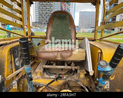 Telaio panoramico sedile e avambracci di comando all'interno della cabina aperta di un macchinario per impieghi gravosi. Foto Stock