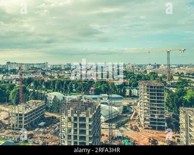 costruzione di edifici a più piani nel centro della città. case alte fatte di blocchi e lastre di cemento. gru pesante, gialla, in metallo, solleva edifici ma Foto Stock