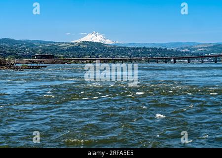 Il Dalles Bridge attraversa il fiume Columbia tra Oregon e Washington e Mount Hood che si innalza dietro di esso Foto Stock