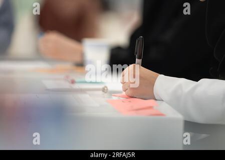 Un uomo arabo che prende appunti in una riunione al lavoro Foto Stock