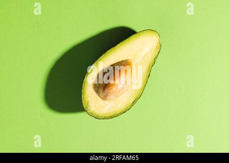 Primo piano dell'avocado dimezzato e dello spazio di copia su sfondo verde Foto Stock