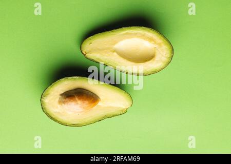 Primo piano di due metà di avocado e spazio di copia su sfondo verde Foto Stock