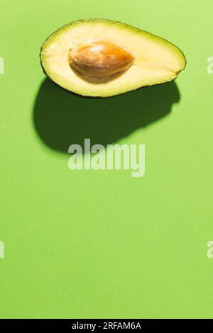 Primo piano dell'avocado dimezzato e dello spazio di copia su sfondo verde Foto Stock