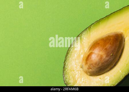 Primo piano dell'avocado dimezzato e dello spazio di copia su sfondo verde Foto Stock