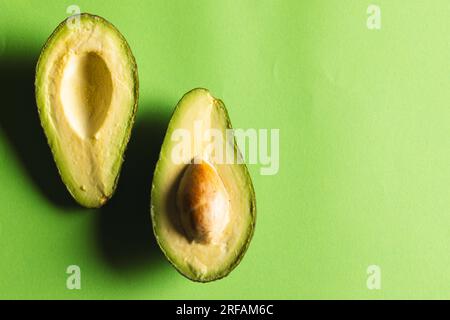 Primo piano di due metà di avocado e spazio di copia su sfondo verde Foto Stock