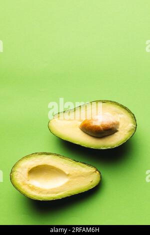 Primo piano dell'avocado dimezzato e dello spazio di copia su sfondo verde Foto Stock