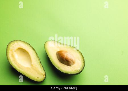 Primo piano di due metà di avocado e spazio di copia su sfondo verde Foto Stock