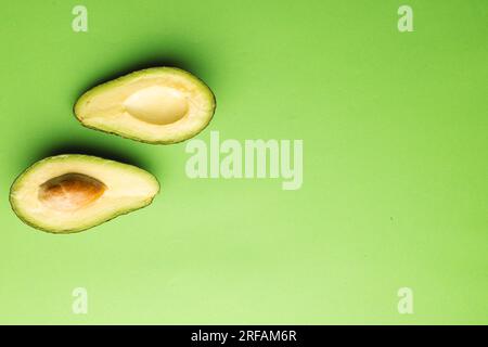 Primo piano di due metà di avocado e spazio di copia su sfondo verde Foto Stock