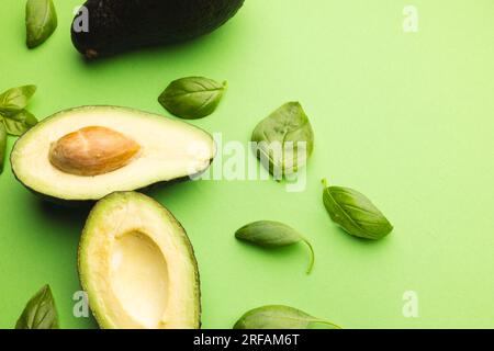 Primo piano di due metà di foglie di avocado e basilico e spazio di copia su sfondo verde Foto Stock