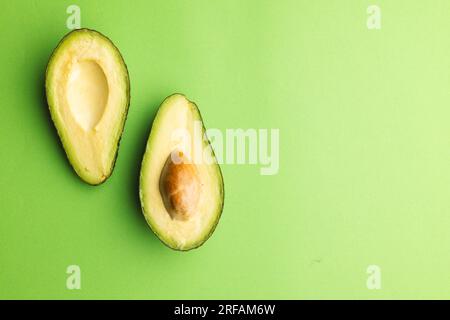 Primo piano di due metà di avocado e spazio di copia su sfondo verde Foto Stock