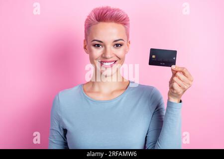 Foto di adorabili donne positive che indossano abiti blu alla moda che dimostrano il pagamento con carta di plastica nfc isolato su sfondo rosa Foto Stock