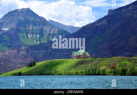 vista dell'iconico hotel prince of wales e delle montagne rocciose canadesi attraverso i laghi di waterton color turchese in estate, a waterton, alberta, canada Foto Stock