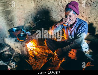 14 ottobre 2022 Uttarakhand, India. Anziani nativi che si godono il tè nella tradizionale casa di fango con stufa in argilla a Garhwal, Himalaya. Ricco patrimonio culturale c Foto Stock