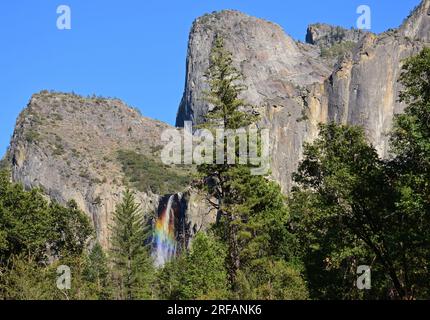 l'arcobaleno colorato delle cascate di bridalveil accanto alle formazioni rocciose del fratello medio e del fratello inferiore nella valle di yosemite, nel parco nazionale di yosemite, in california Foto Stock