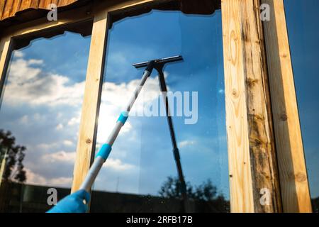 Vista ritagliata dell'attrezzatura per le mani delle donne per lavare e pulire la finestra dall'esterno Foto Stock