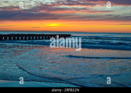 Un meraviglioso e scintillante cielo all'alba sulla spiaggia e il molo di legno del Lido di Jesolo, popolare località estiva sulla costa adriatica, vicino a Venezia, Veneto, Italia. Foto Stock