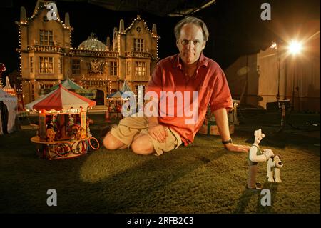 Ritratto di Nick Park, creatore dei personaggi animati "Wallace and Grommit", raffigurato con uno sfondo che è una scena del suo film, "Wallace and Grommit,The Curse of the Were-Rabbit" presso i suoi studi Aardman, Bristol, Regno Unito. Foto Stock