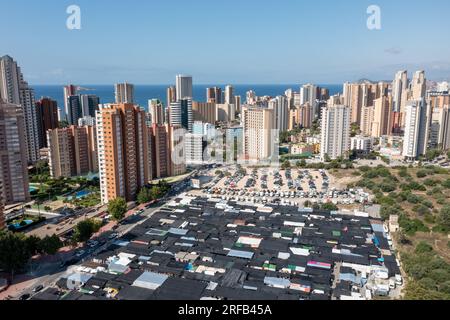 Foto aerea con drone della città di Benidorm in Spagna nel periodo estivo che mostra il famoso mercato e le bancarelle del mercato con il parcheggio e la strada trafficata Alò Foto Stock