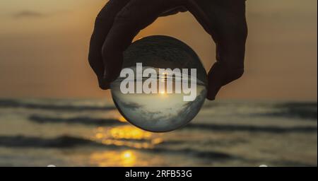 tramonto sulla spiaggia visto con la sfera di cristallo Foto Stock