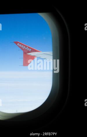 Vista dalla finestra di un aereo o di un aereo di linea che mostra l'ala del jet e un cielo blu profondo. Foto Stock