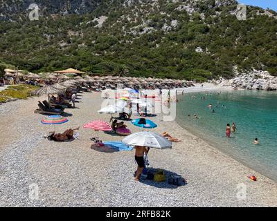 Skopelos, Grecia. 2 agosto 2023. Le persone trascorrono la calda giornata estiva su una spiaggia sull'isola di Skopelos. Alcuni si siedono sotto i propri ombrelli colorati, altri sotto gli ombrelli di paglia che possono essere noleggiati. Ciò è corretto anche secondo la legge greca, che stabilisce che i cittadini devono avere libero accesso alle spiagge, che sono in ogni caso pubbliche. La legge greca non riconosce le spiagge private. Credito: Alexia Angelopoulou/dpa/Alamy Live News Foto Stock