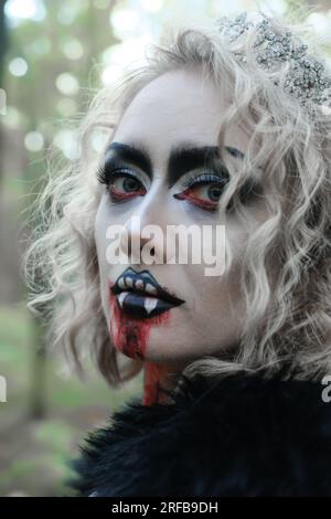 Una donna sotto forma di vampiro o strega con trucco bianco in faccia. donna che guarda la telecamera. Foto verticale Foto Stock