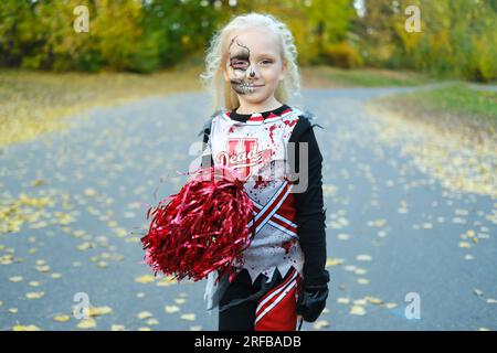 Una ragazza con un costume da cheerleader e un trucco a mezza faccia sotto  forma di scheletro celebra Halloween. Foto orizzontale Foto stock - Alamy