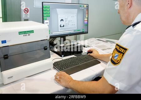 02 agosto 2023, Baviera, Norimberga: Un agente di polizia della polizia di frontiera bavarese verifica l'autenticità di una carta d'identità all'aeroporto, risulta essere un falso. La polizia di frontiera ha iniziato il suo lavoro il 1 luglio 2018. Foto: Daniel Löb/dpa Foto Stock